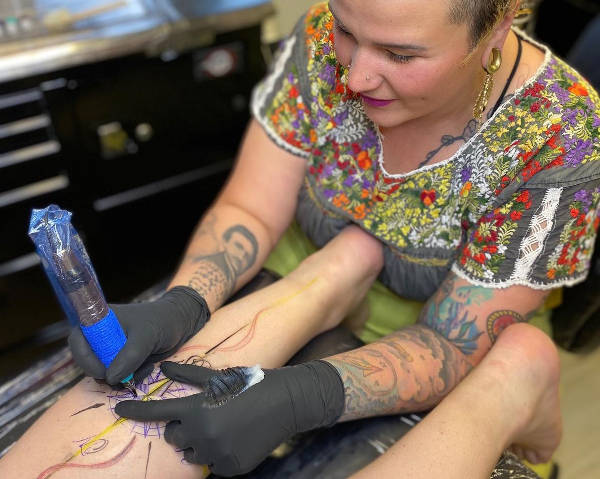 Lola tattoing a client's wrist
